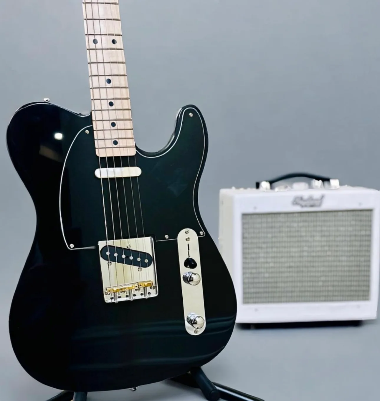 Black nitro custom Fayland guitar with fayland guitar amp in background.